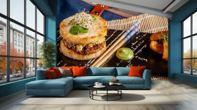 Pan-Asian cuisine concept. Japanese sushi burger made from rice bread, chicken and pork meat patties, lettuce and wasabi sauce. Serving dishes with french fries. copy space Wall mural