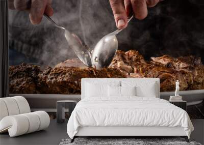 The chef uses two spoons to tear apart a large fried piece of meat that is smoking. background image. Wall mural