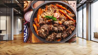 The concept of Uzbek, oriental cuisine. Pilaf in a cast-iron pan, with pieces of lamb lies on a wooden table. Festive table set. Wall mural