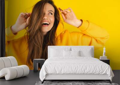 Close up photo of trendy cheerful cute nice sweet youngster laughing looking away toothy wearing hood isolated over yellow color background. Funny girl look playful holding hood. Wall mural