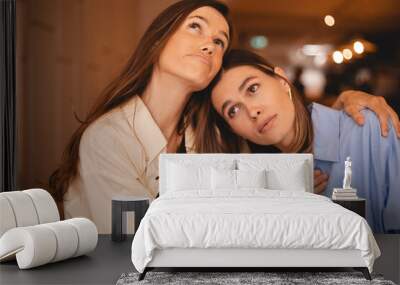 Portrait of displeased young woman and best female friends sisters trying to comfort and cheer up sitting together in cafe. Women hugging to support her friends. Bad news. Wall mural