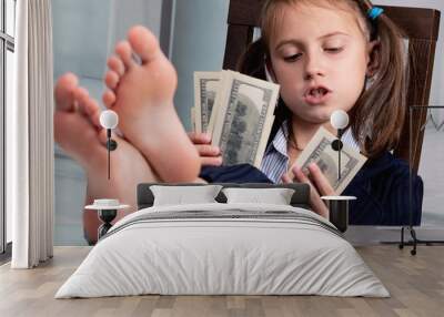 Close up humorous portrait of happy cute young business girl counts US Dollar money profit with bare feet on the table. Selective focus on eyes of girl. Wall mural