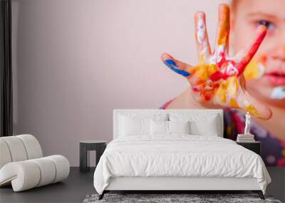 Hands and face of cute young girl painted in colorful paints. Children's makeup. Copy space. Wall mural