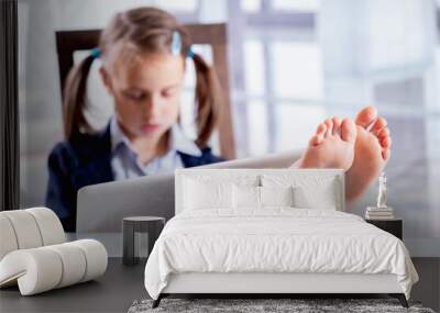 Humorous image of business child girl with bare feet on the table is working in office after lockdown. Selective focus on  bare feet Wall mural