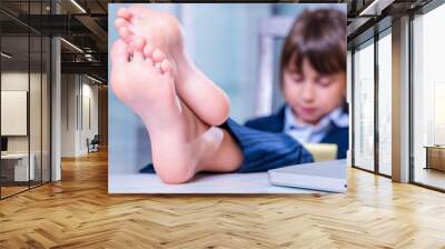 Humorous portrait of cute little business child girl with bare feet works with laptop. Selective focus on bare feet. Wall mural