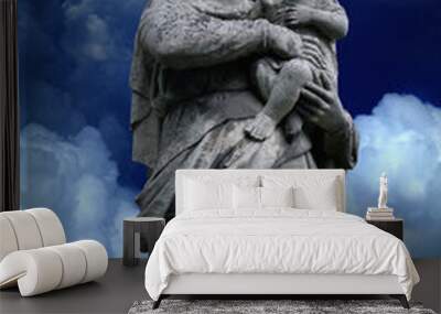 Queen of Heaven. Virgin Mary with baby Jesus Christ. An ancient statue against blue sky background. Wall mural