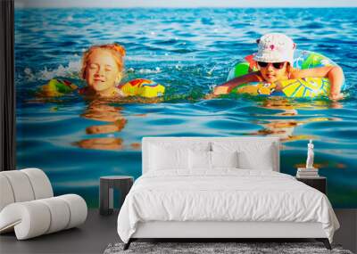 Twoo happy child girls swimming in the sea. Kids having fun outdoors with water. Summer vacation and healthy lifestyle concept. Wall mural