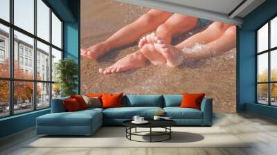 Vacation and holidays concept. Feet of two young girls relaxing on beach enjoying sun and sea on sunny summer day. Wall mural