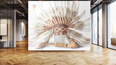 An Indian hat with feathers on a crystal vase and a wooden smoking pipe. Wall mural