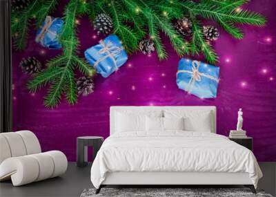 spruce green branch with gifts and fir cones on purple wooden background Wall mural