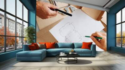 Box makers working behind a table, discussing schematics of a box Wall mural