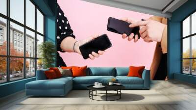 close-up screens phones in the hands of men and women on a pink background. Wall mural