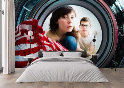 Funny couple loading clothes to washing machine. From inside the washing machine view Wall mural