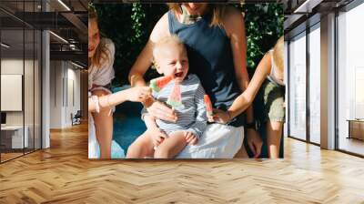 Happy family sitting together, eating watermelon ice cream. Wall mural