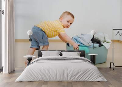 Little boy pushes basket with clean laundry after washing. High quality photo Wall mural