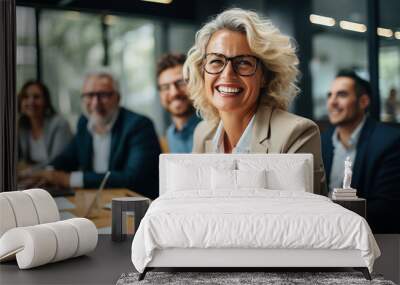 Group of adults led by a smiling mature business woman in her 50s in a conference room Wall mural