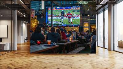 People enjoying an outdoor sports bar with large screen showing football game Wall mural