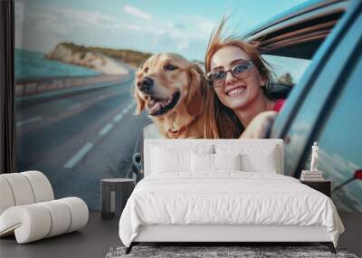 happy young woman with cute retriever dog leaning out of open car window while driving on highway in nature on sunny joyful summer day, travel concept Wall mural