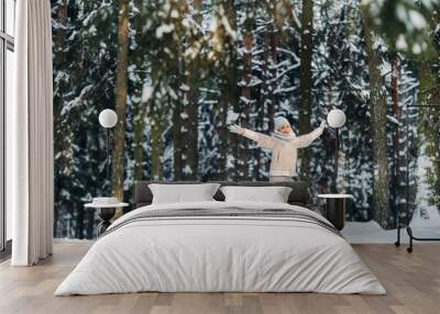 a woman in gray clothes jumps emotionally in a winter forest.Girl in the new year's snow-covered forest. Wall mural