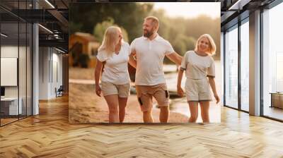 Happy family - father, mother and daughter in light clothes having fun together on the beach in summer Wall mural