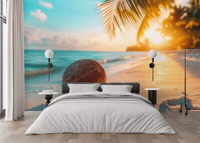 Coconut lying on a tropical beach at sunset with palm trees Wall mural