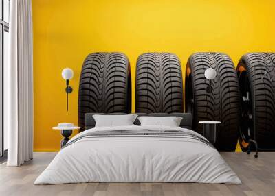 Four tires standing on a yellow background Wall mural