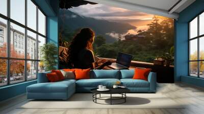 Young woman freelancer traveler working online using laptop and enjoying the beautiful nature landscape with mountain view at sunrise Wall mural