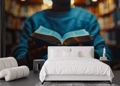 of close-up of a black anonymous person hands gently turning the pages of an open book on table with a warm light overhead Wall mural