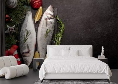 Raw sea bass fish with spices for the Christmas holiday on a stone background with a Christmas tree and new year toys  with copy space Wall mural