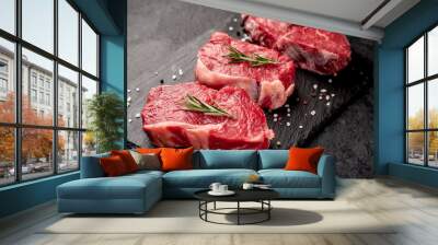 raw three beef steaks on a cutting board with spices on a stone background Wall mural