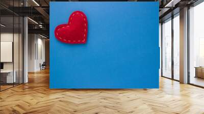 Red heart fabric with white threads on a blue background Love, romance concept. Felt bright hearts with embroidered lines. Wall mural