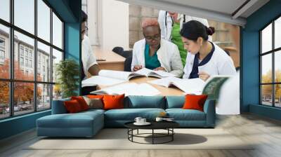 A group of mixed race doctors discussing medicine in the office at the table. Wall mural