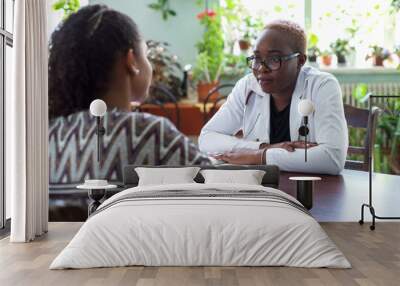 young hispanic girl patient receiving black female doctor at office. Confidence of the patient and the doctor Wall mural