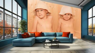 Two little boy, with bath hats on their heads and turned into white sheets looking on each other, beauty and health concept, indoor closeup portrait. Wall mural