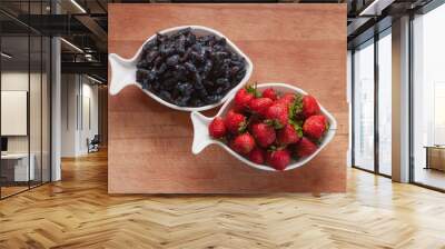 Strawberries and blueberries in porcelain cups on a wooden background. Berry mix. Dishes in the shape of the zodiac sign Pisces. Diet breakfast. Wall mural