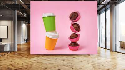 several flying cupcakes and two glasses for coffee and tea on a pink background. Wall mural