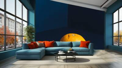 A ripe orange stands in the corner of the room in a dark blue tone . The concept of proper nutrition and a healthy lifestyle. Wall mural