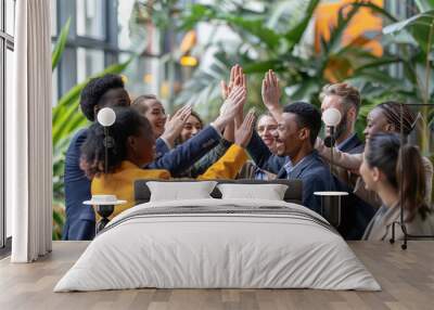 Group of diverse young professionals giving high fives in a modern office Wall mural