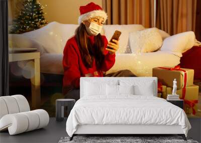 Happy woman with face mask home alone in lockdown celebrating christmas online video calling family and friends. Virtual holiday gathering and celebrations due to coronavirus second outbreak. Wall mural