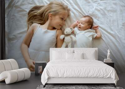 Little sister and her newborn brother. Toddler kid meeting new sibling. Cute girl and new born baby boy relax in a home bedroom. Family with two children at home. Love, trust and tenderness concept Wall mural