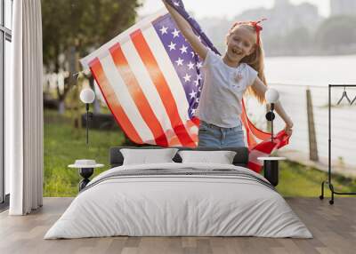 Patriotic holiday. Happy family, mother and daughter with American flag outdoors on sunset. USA celebrate independence day 4th of July. Wall mural