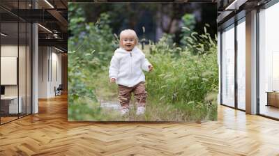 Portrait of cute little caucasian baby girl one year old takes the first steps and learns to walk in park at autumn. Stylish infant with blonde hair and blue eyes wearing fashionable clothing. Happy Wall mural