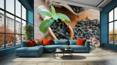 Jute bag with leaf tea, wooden spoon and fresh mint leaves lies on a wooden background Wall mural