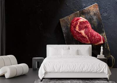  Raw rib eye steak on the board top view on dark stone table with copy space for your text Wall mural