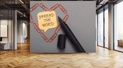 A black pen with a yellow note that says Spread the word Wall mural