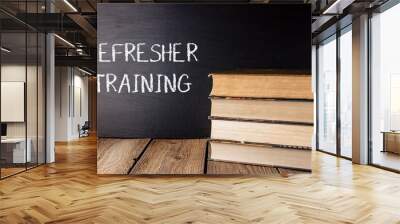 A stack of books with the word refresher training written on a chalkboard Wall mural