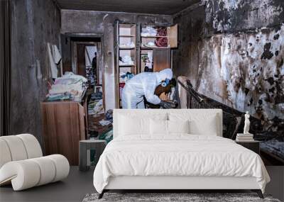 a specialist in a protective suit from a cleaning company cleans a destroyed housing after a fire Wall mural