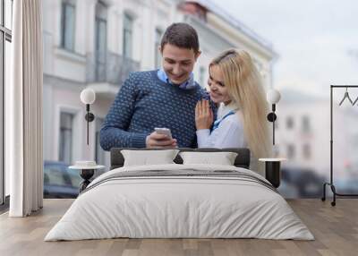 girl blond and guy looking something in the mobile phone and smi Wall mural