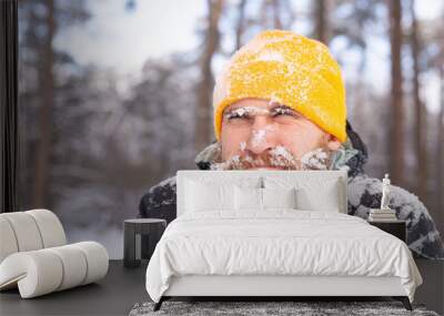 An adult brutal man with a beard in a winter forest all face in the snow, frozen, unhappy with the cold Wall mural