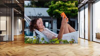 Woman with phone resting lying on hammock with mobile phone, take selfie, chat.   Wall mural